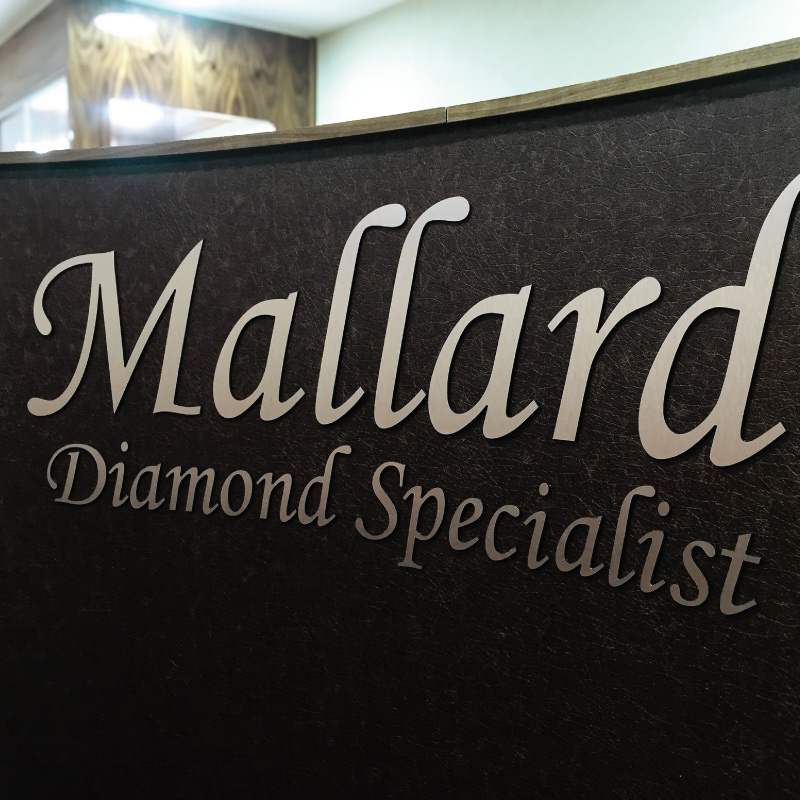 Silver flat cut letters applied to a black front desk area.