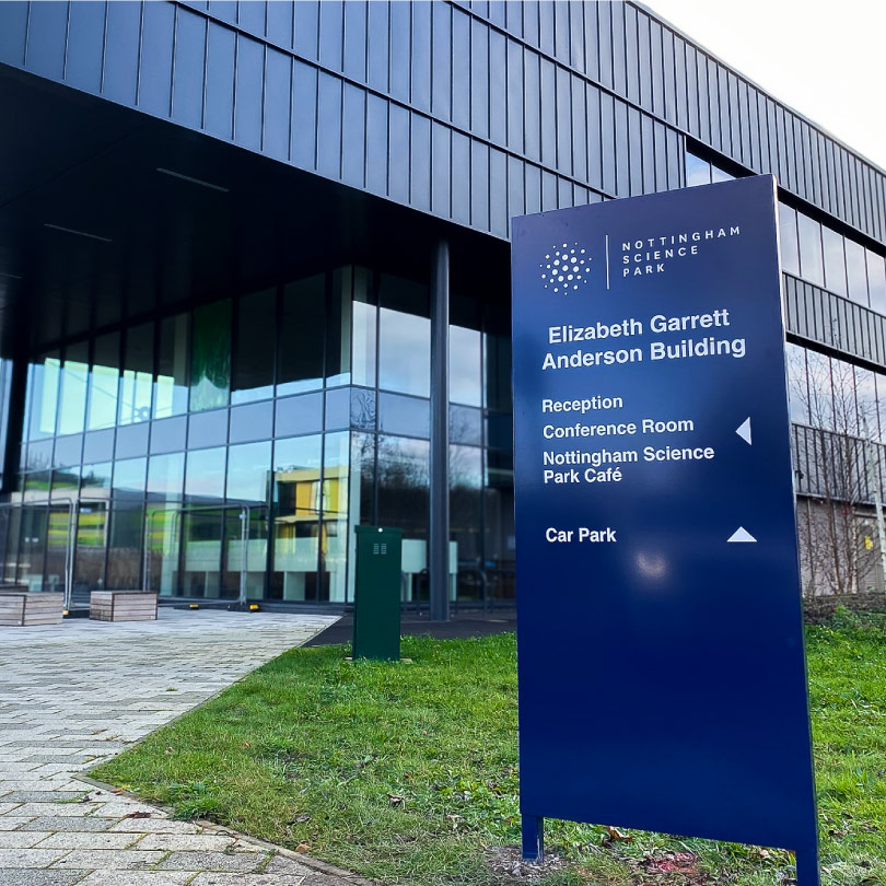 The image shows a tall blue Nottingham Science Park sign in front of a modern multi-story building.