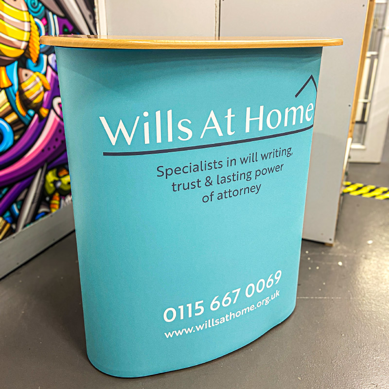 An Exhibition Stand that is blue and features the Wills at Home logo