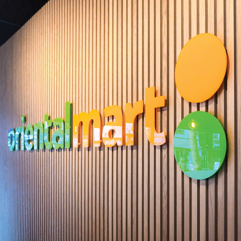 Vertical thin wood panels with the oriental mart logo in acrylic cut letters on standoffs