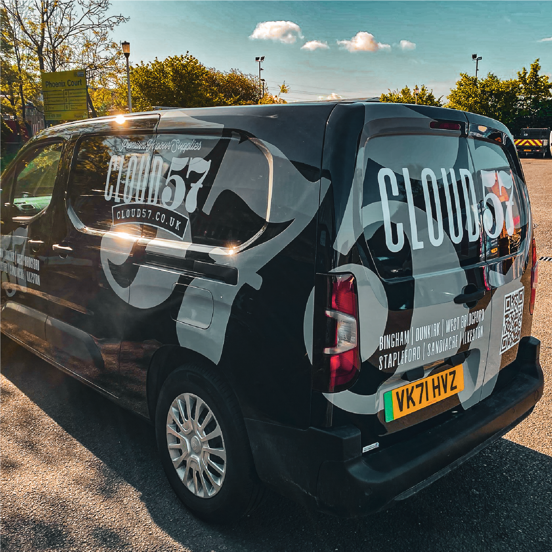 The back corner of a black van with a large 57 graphic on. Over the top of this it says 'Cloud 57' and 'Premium Vapour Supplies'. There is a list of shop locations and a QR code on the back of the van.